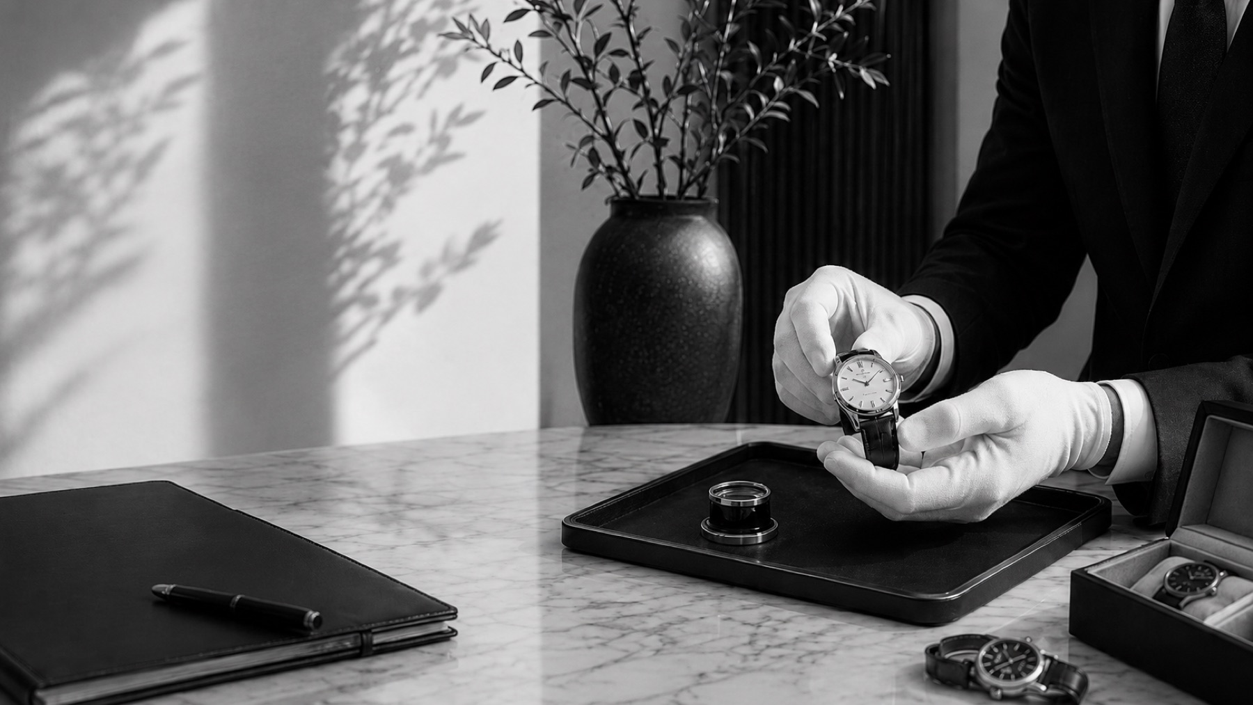 A white-gloved specialist presenting a watch on a tray